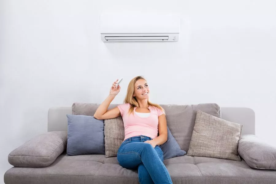 Image of a person sitting on a couch below a ductless system. Planning to Remodel? Go Ductless!